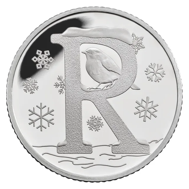 A robin perched inside a large letter R topped with snow, surrounded by snowflakes